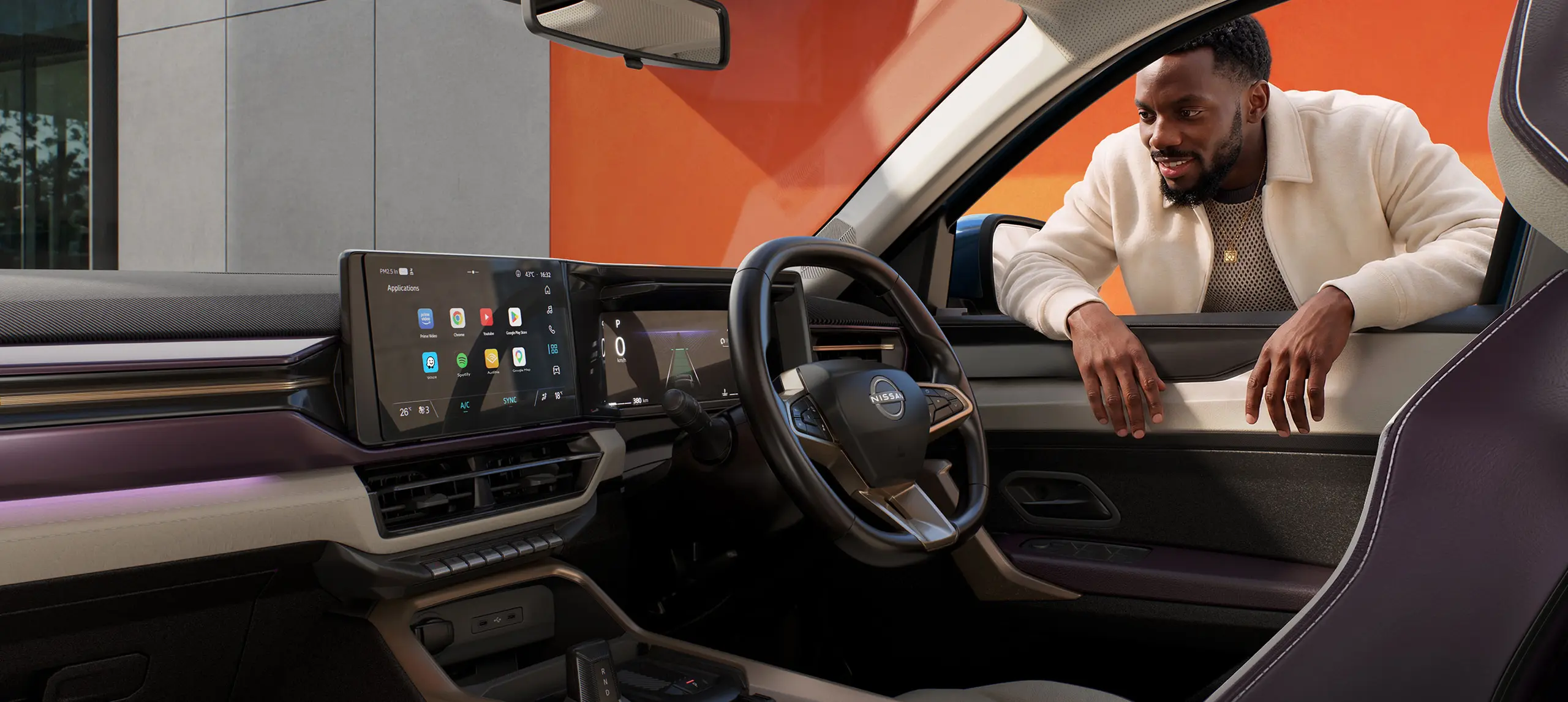 Man leaning into the open car door, smiling at the luxury sedan’s high-tech dashboard and steering wheel with Nissan logo.