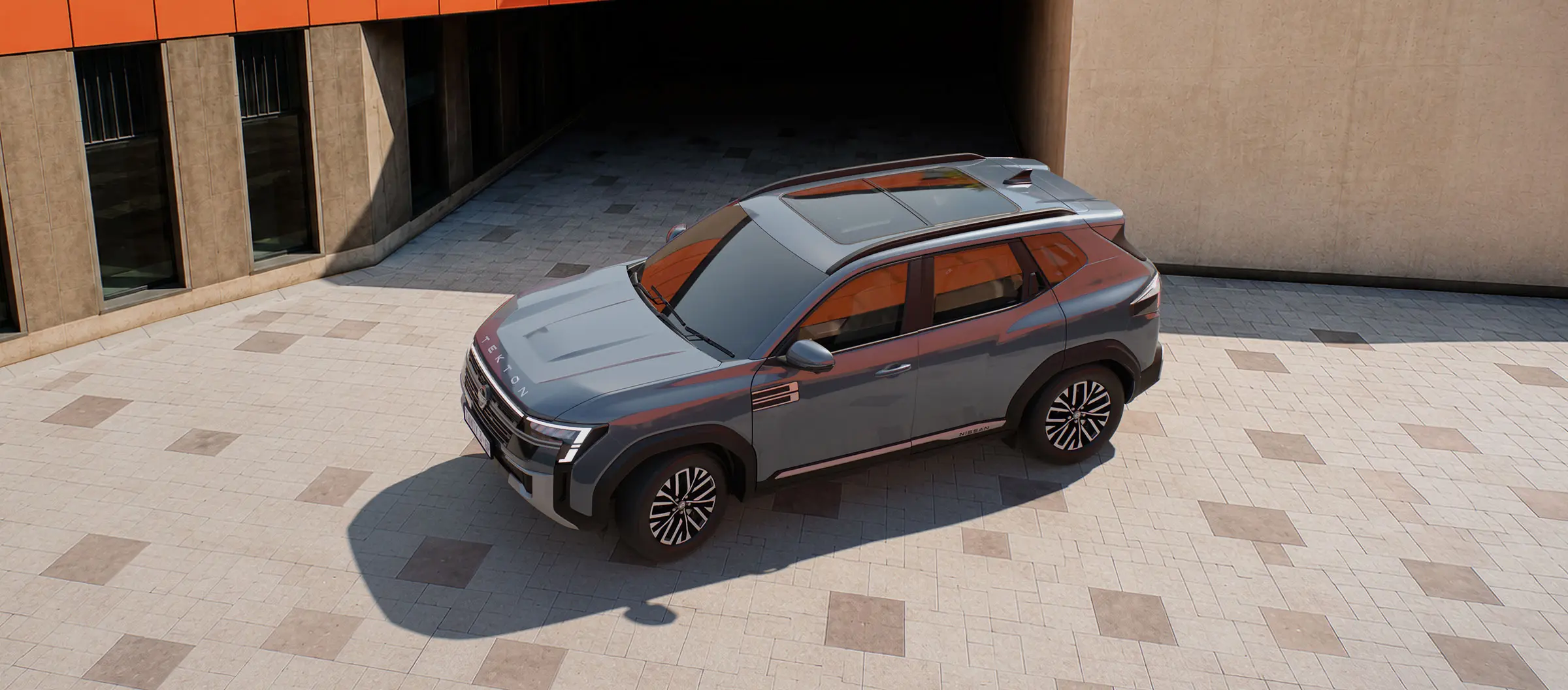 Gray Nissan SUV parked on a light-tiled plaza beside a beige building with an orange canopy.