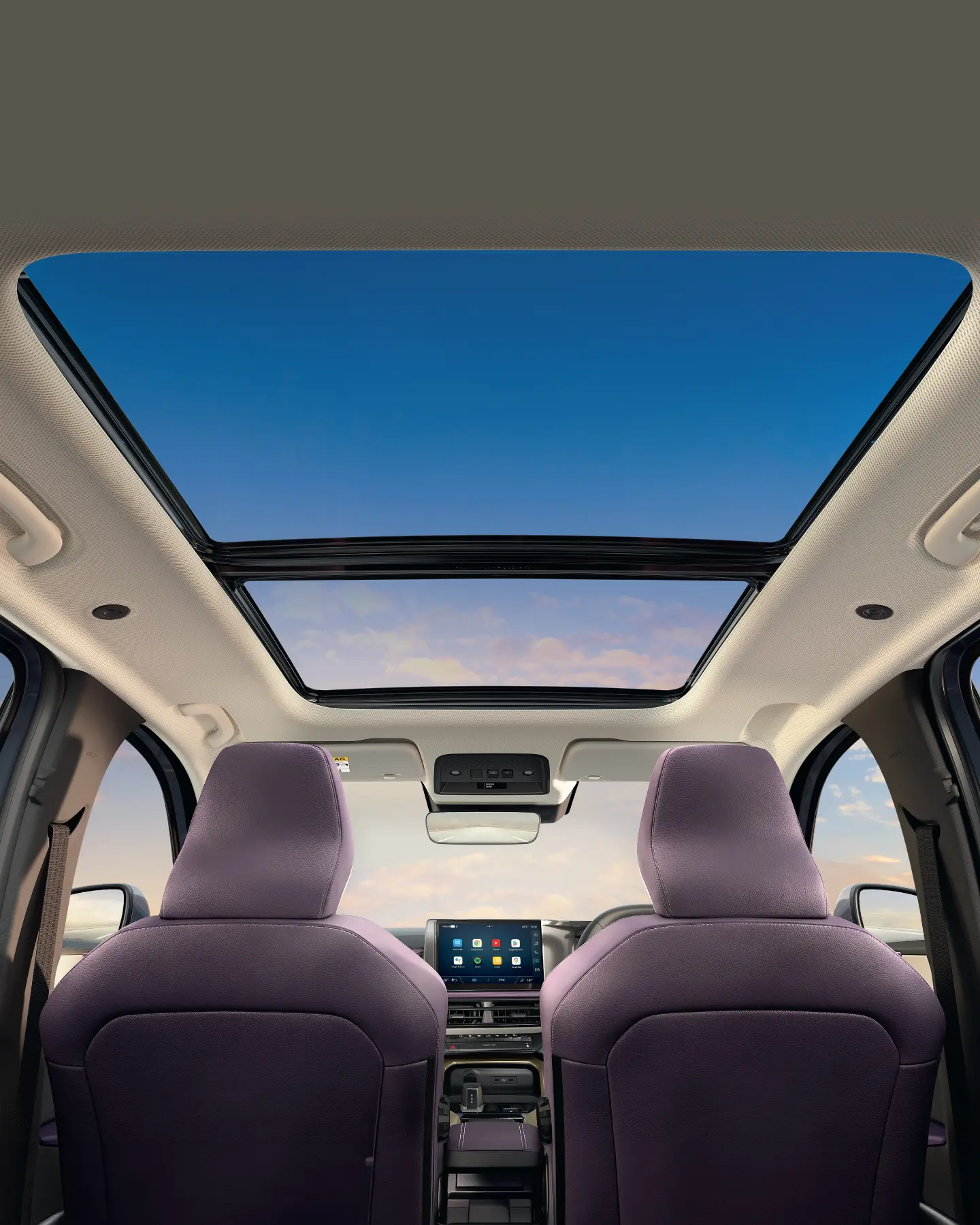 Interior of a car with purple seats and a large panoramic sunroof, blue sky visible.