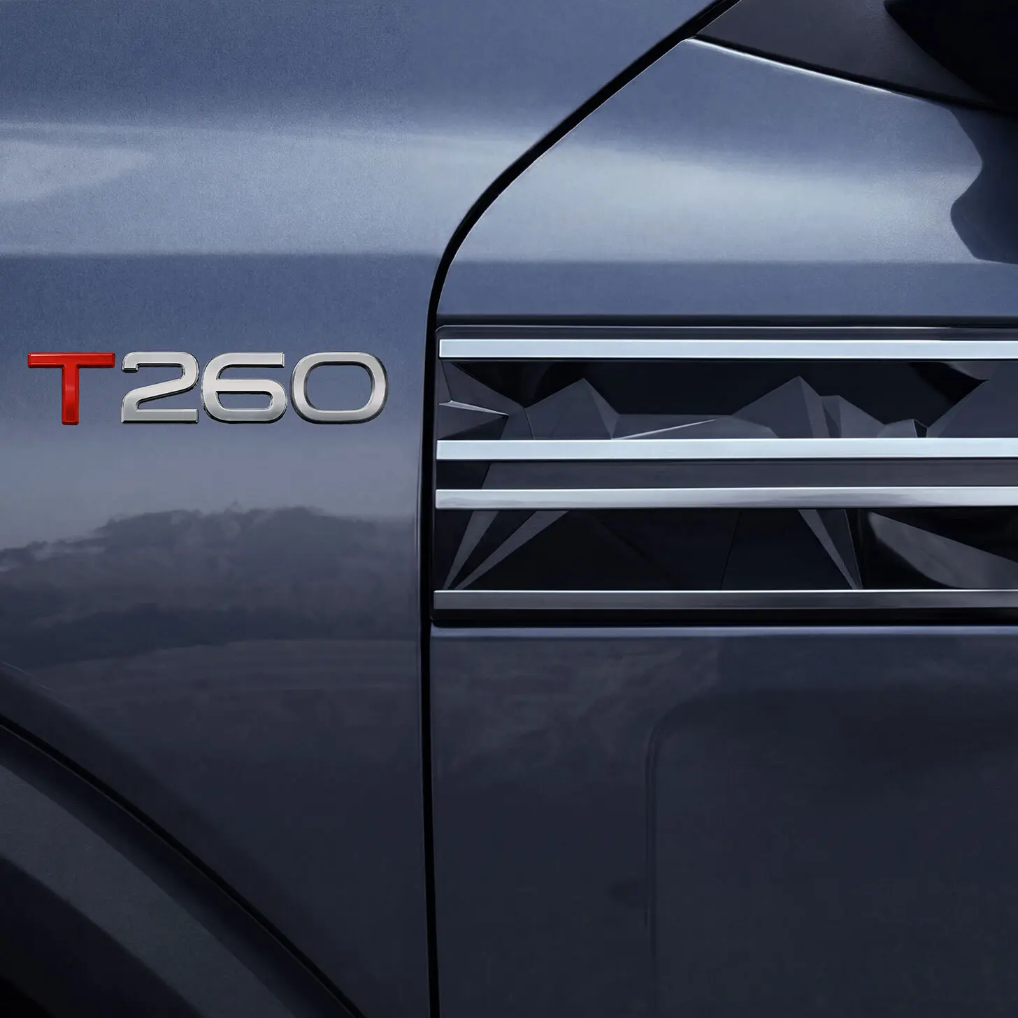 Close-up of a car door badge reading T260 on a metallic blue vehicle side.